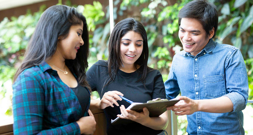picture of centennial college students in the progress campus library looking at a clip board